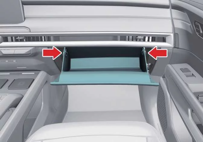 Pressing the side panels inward to drop down the glove box door in a Kia Telluride